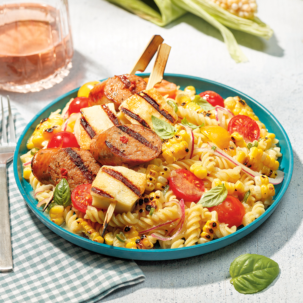 Salade de pâtes au maïs avec brochettes de saucisses et halloumi grillés.