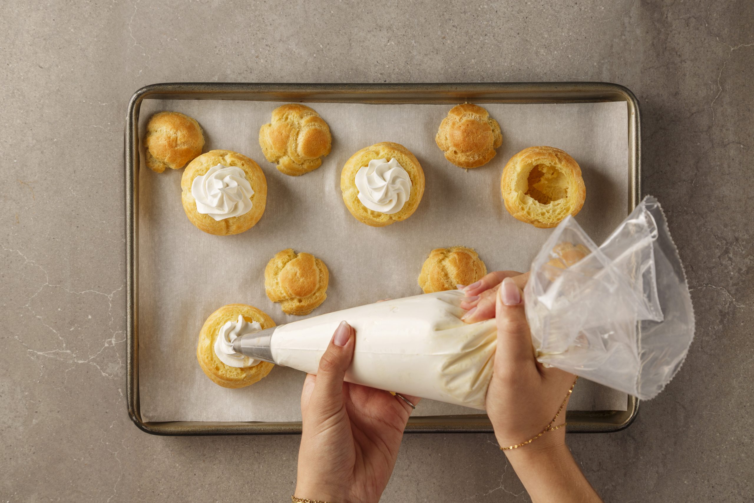 Choux ouverts garnis de crème fouettée à la vanille à la poche à pâtisserie
