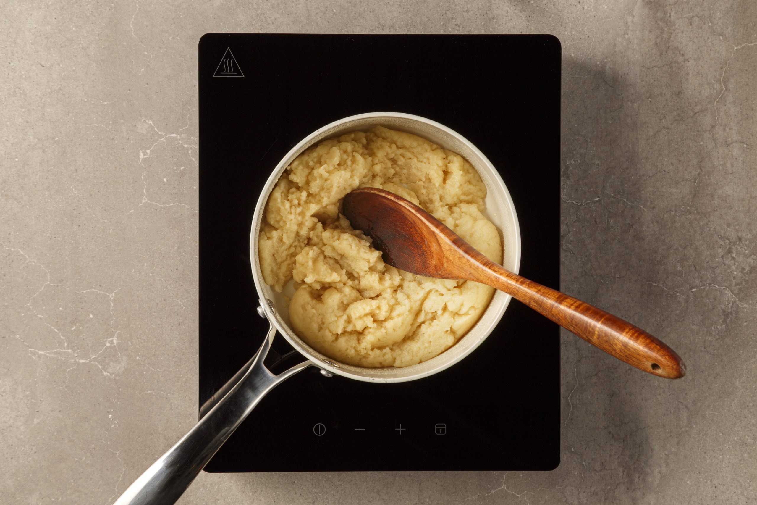 Pâte à choux mélangée dans une casserole avec une cuillère en bois