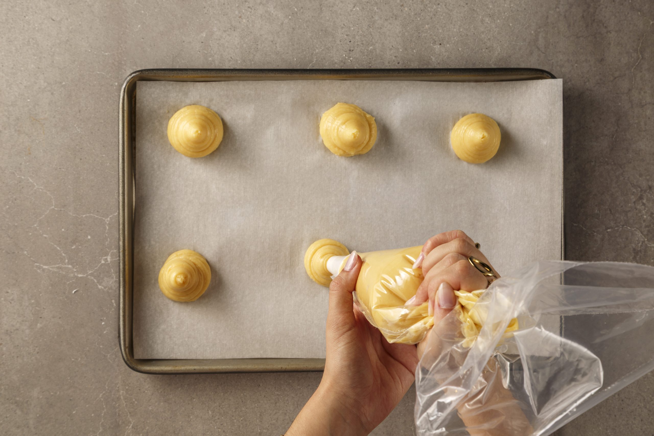 Pâte à choux pochée en petits dômes sur une plaque de cuisson